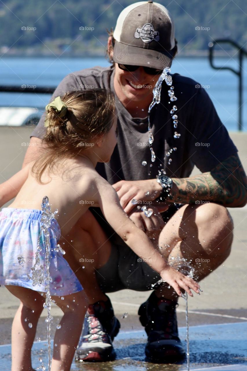 A young father and his daughter play in a water park at Point Ruston in Tacoma, Washington 