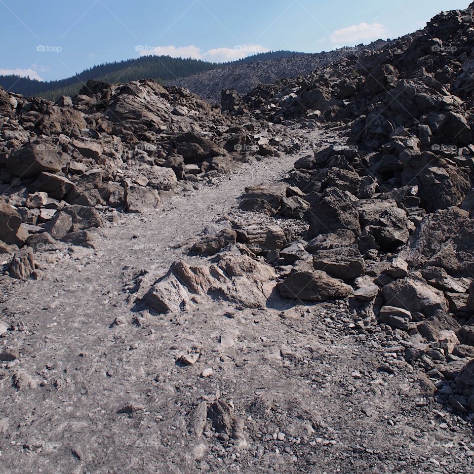 A path runs through the rugged terrain of the jagged rocks at the Big Obsidian Flow in the Newberry National Volcanic Monument in Central Oregon in the fall.
