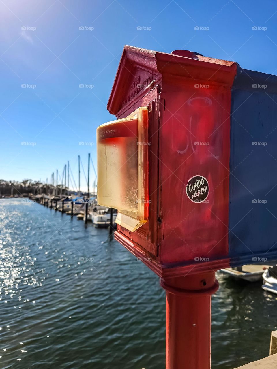 Red and blue emergency box at the end of the marina in San Francisco at the yacht club with the boats and calm waters 