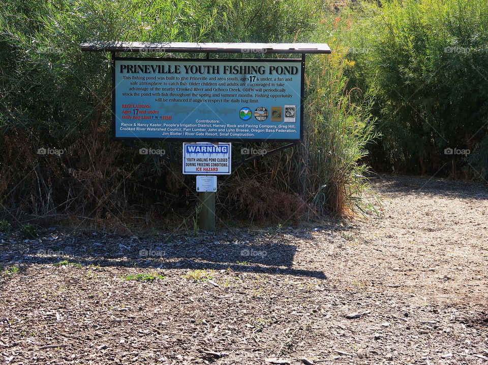 A trail leading to the Prineville Youth Fishing Pond with a sign at Rimrock Park in Prineville on a sunny fall day. 