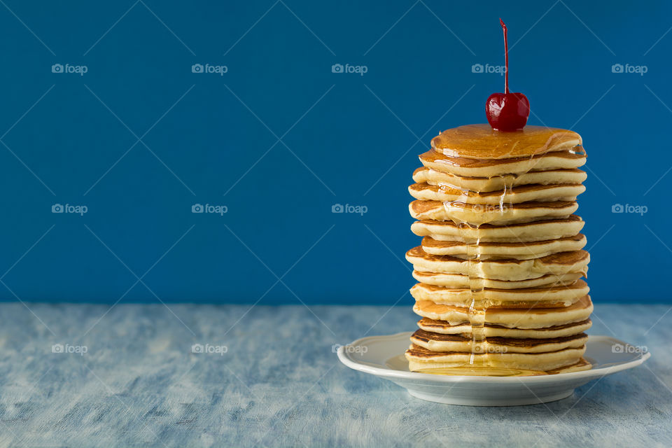 Stack of pancakes with honey and cherry