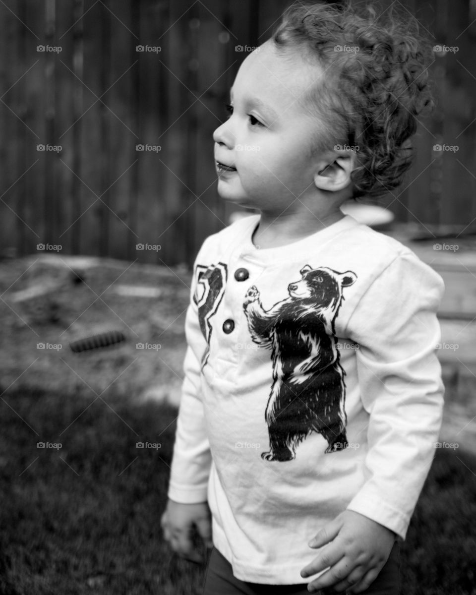 An adorable toddler boy playing in the yard on a sunny summer day. 