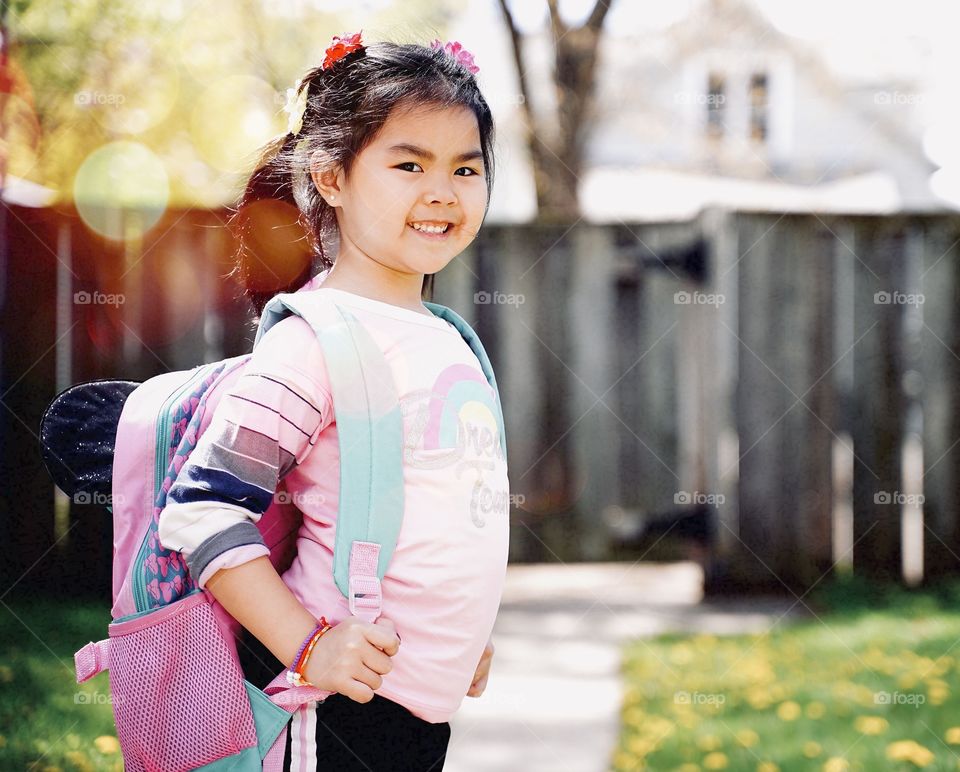 A little girl holding a backpack ready to go to school.  concept back to school.