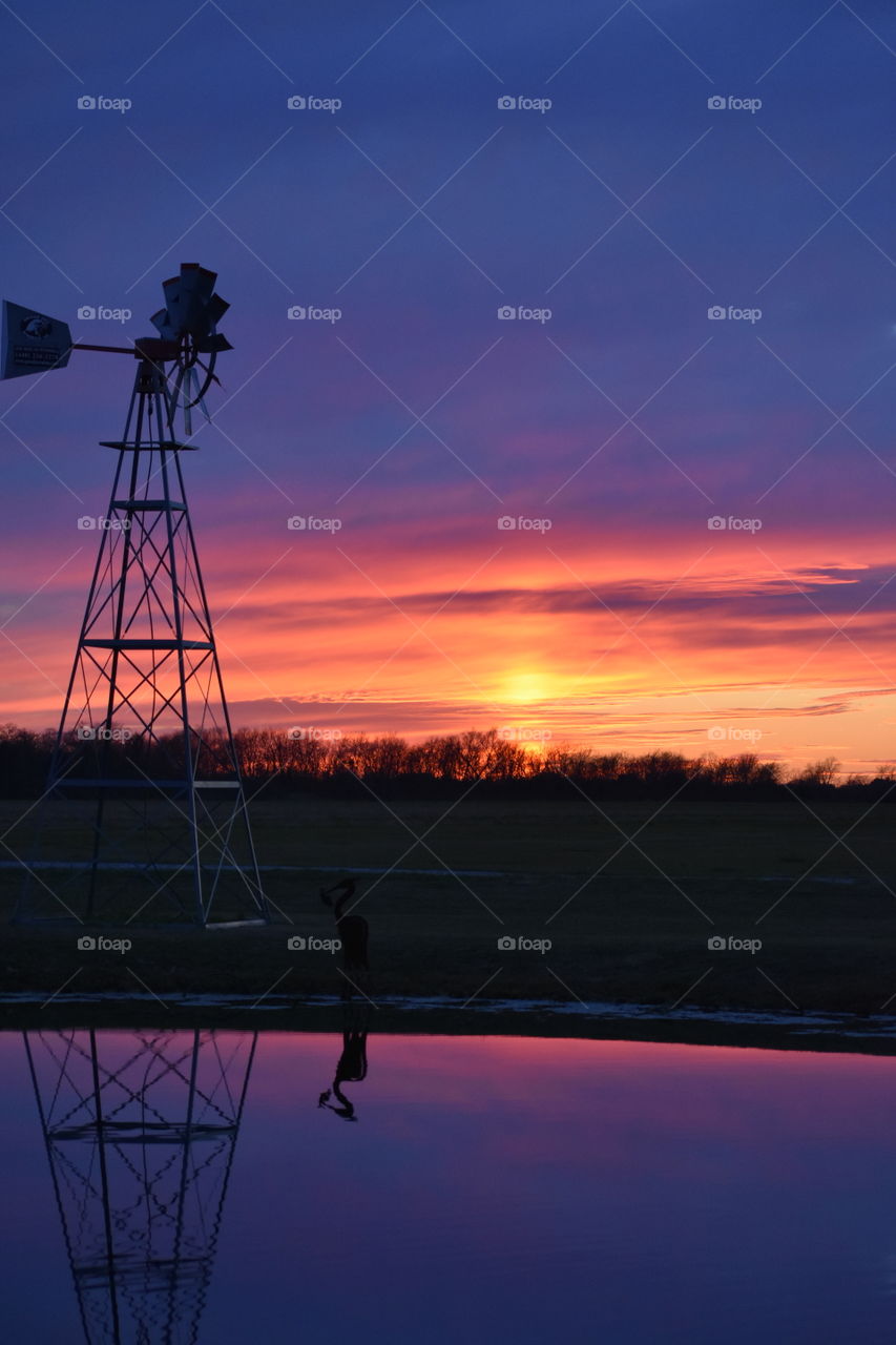 Windmill at lakeside during sunset