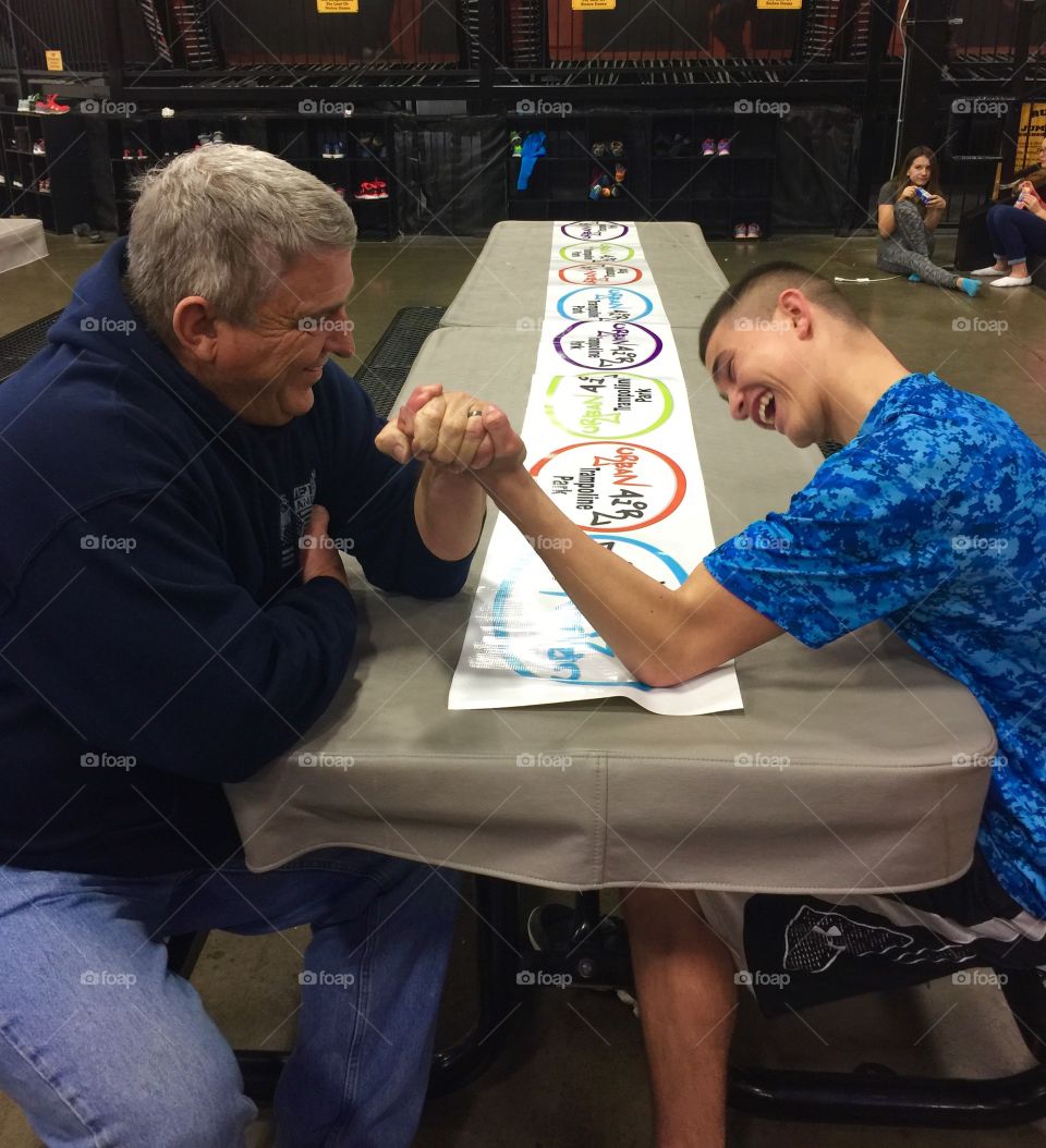 Senior man arm wrestling with teenage boy