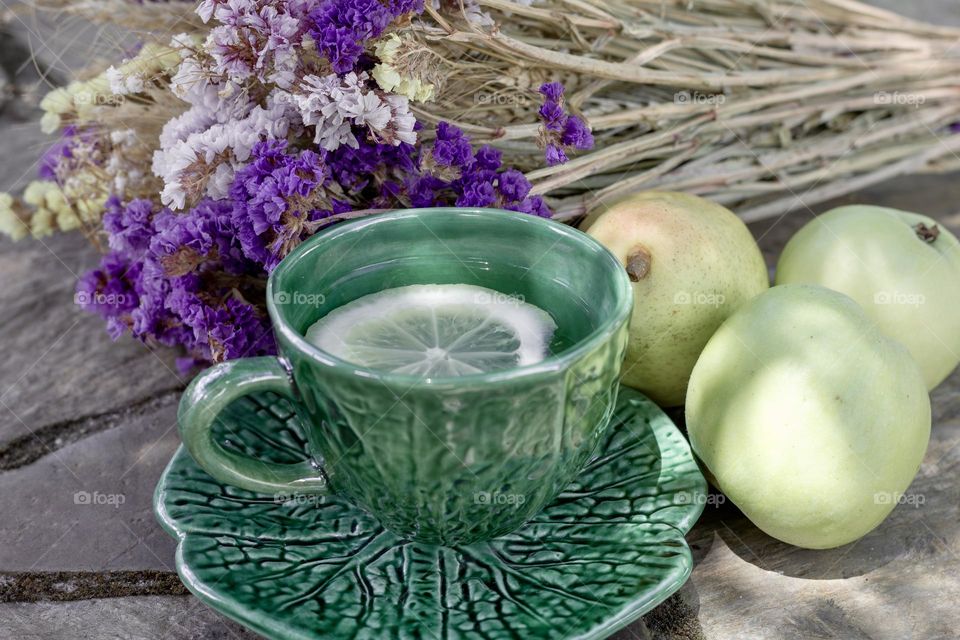 Green cup and apples with dried purple flowers