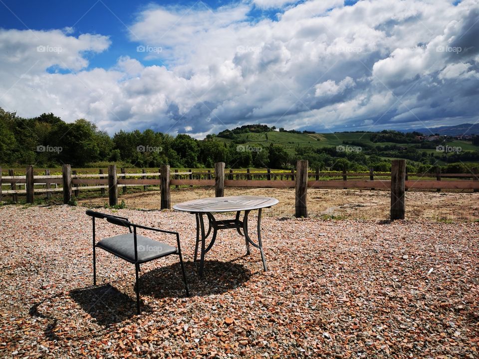 Empty table and chair beside the mountain view with beautiful blue sky and white clouds.