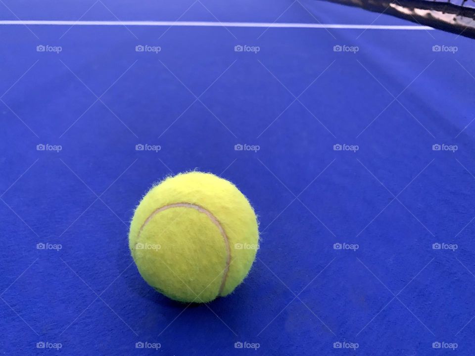 Yellow ball on the blue tennis court
