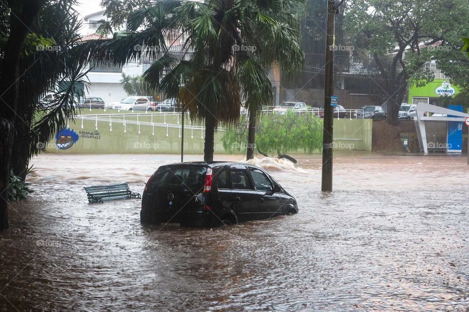 Car on a heavy rain day, on a flood, flooded street at Piracicaba, Brasil. 
Black car on the Waters of a flood in Brazil.