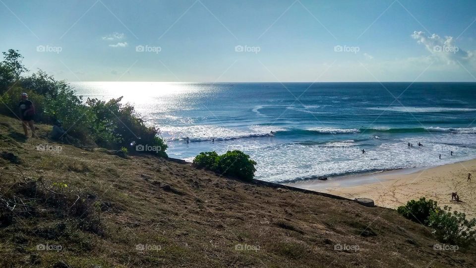 The hillside has a white sand beach as a background in high angle view