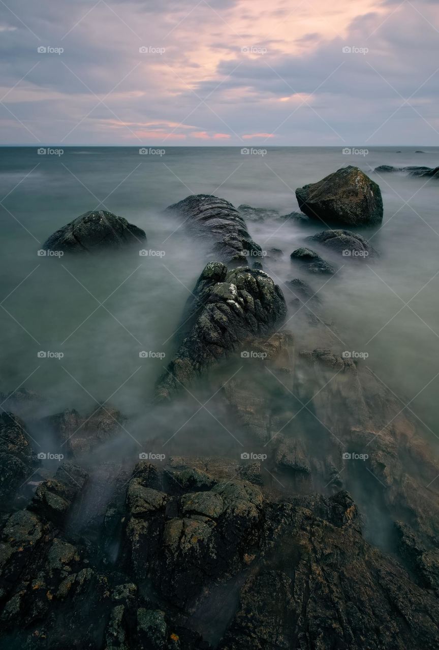 Long exposure of dramatic cloudy sunset scenery at Seaweed beach, county Galway, Ireland