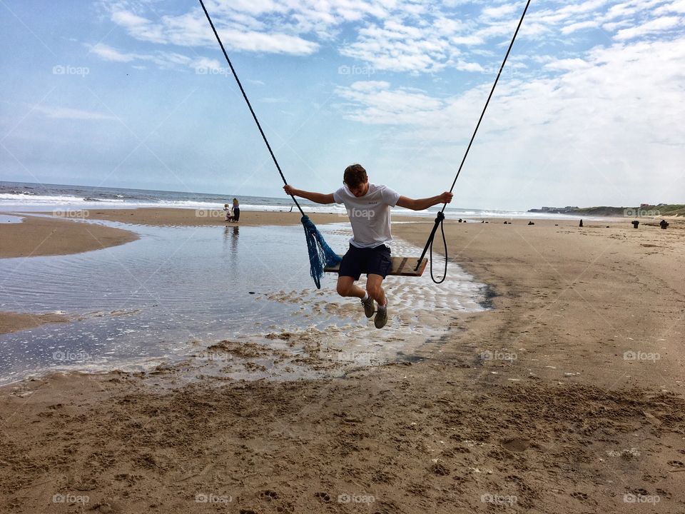 Enjoying freedom after lockdown on the beach … fun on a swing hung under a pier 