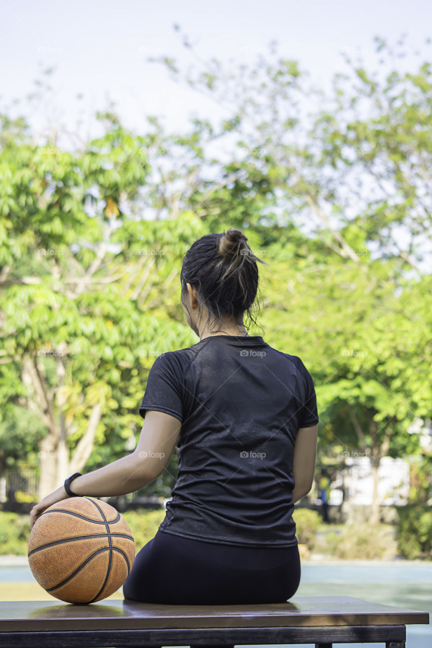 Basketball in hand Asian woman Background blur tree in park.