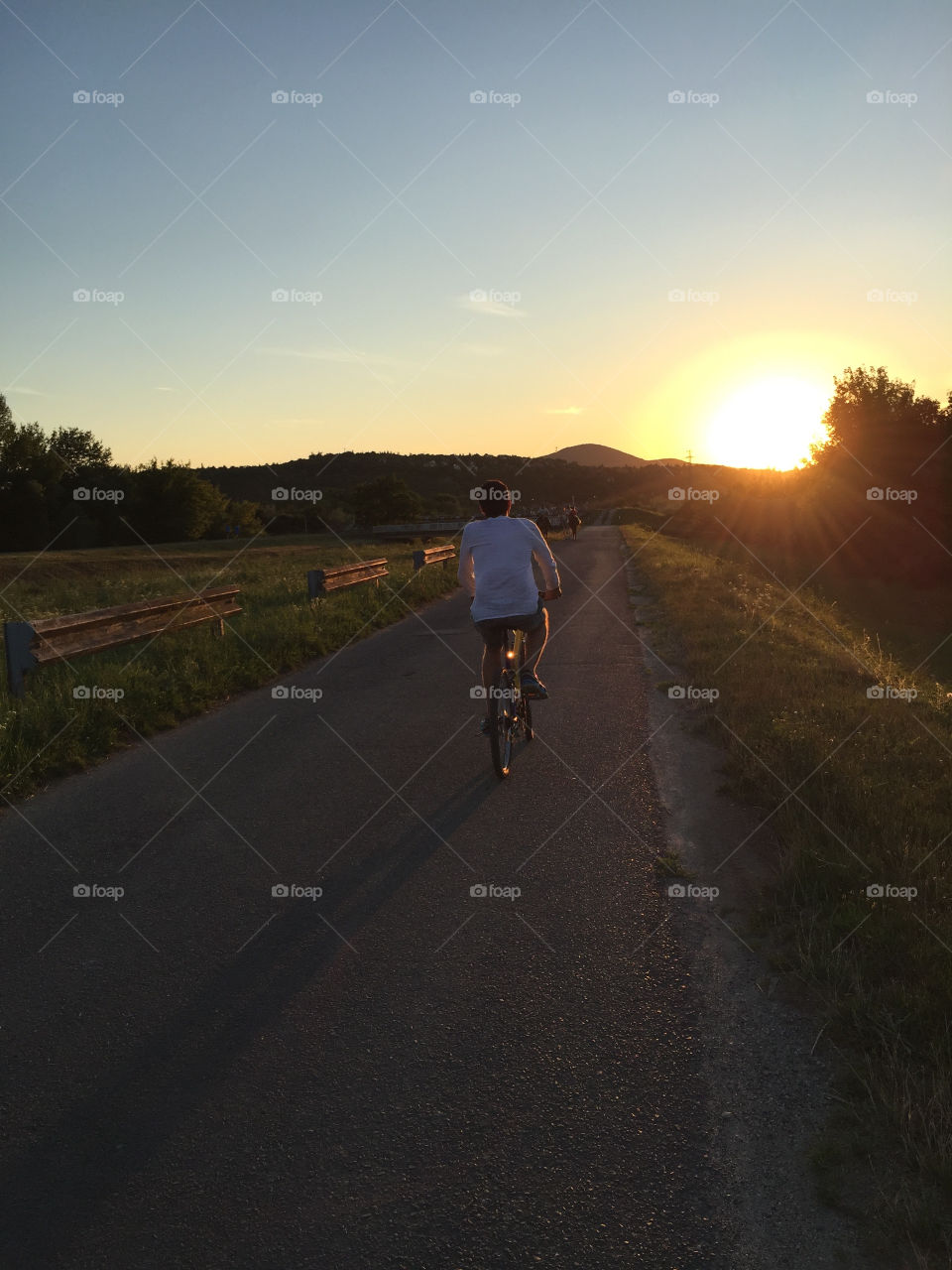 Man cycling on road at sunrise
