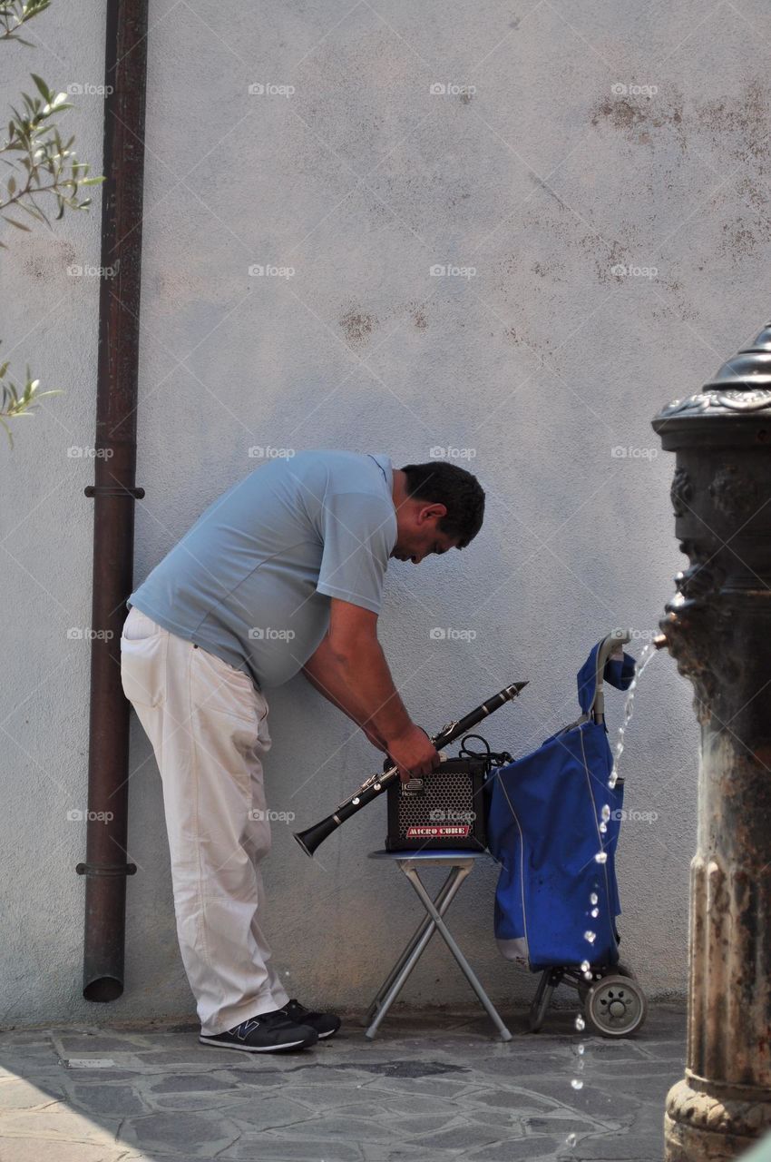 Street artist, traveling artist, turns on the radio to create background music for his next clarinet performance; artist plays the clarinet; clarinet player gettin ready to perform 