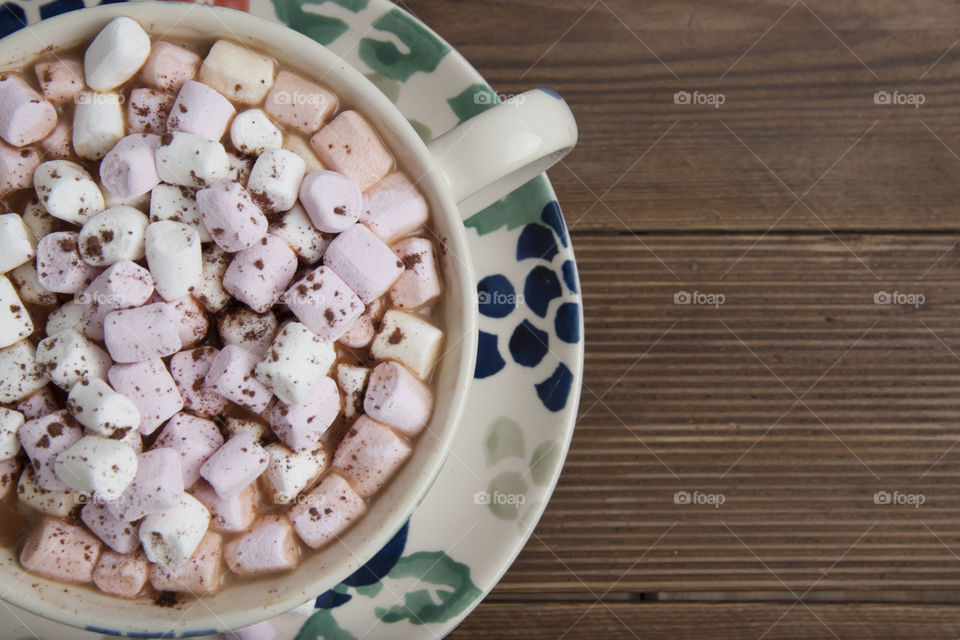 Top view of cocoa cup with marshmellow over wooden background. Square image.