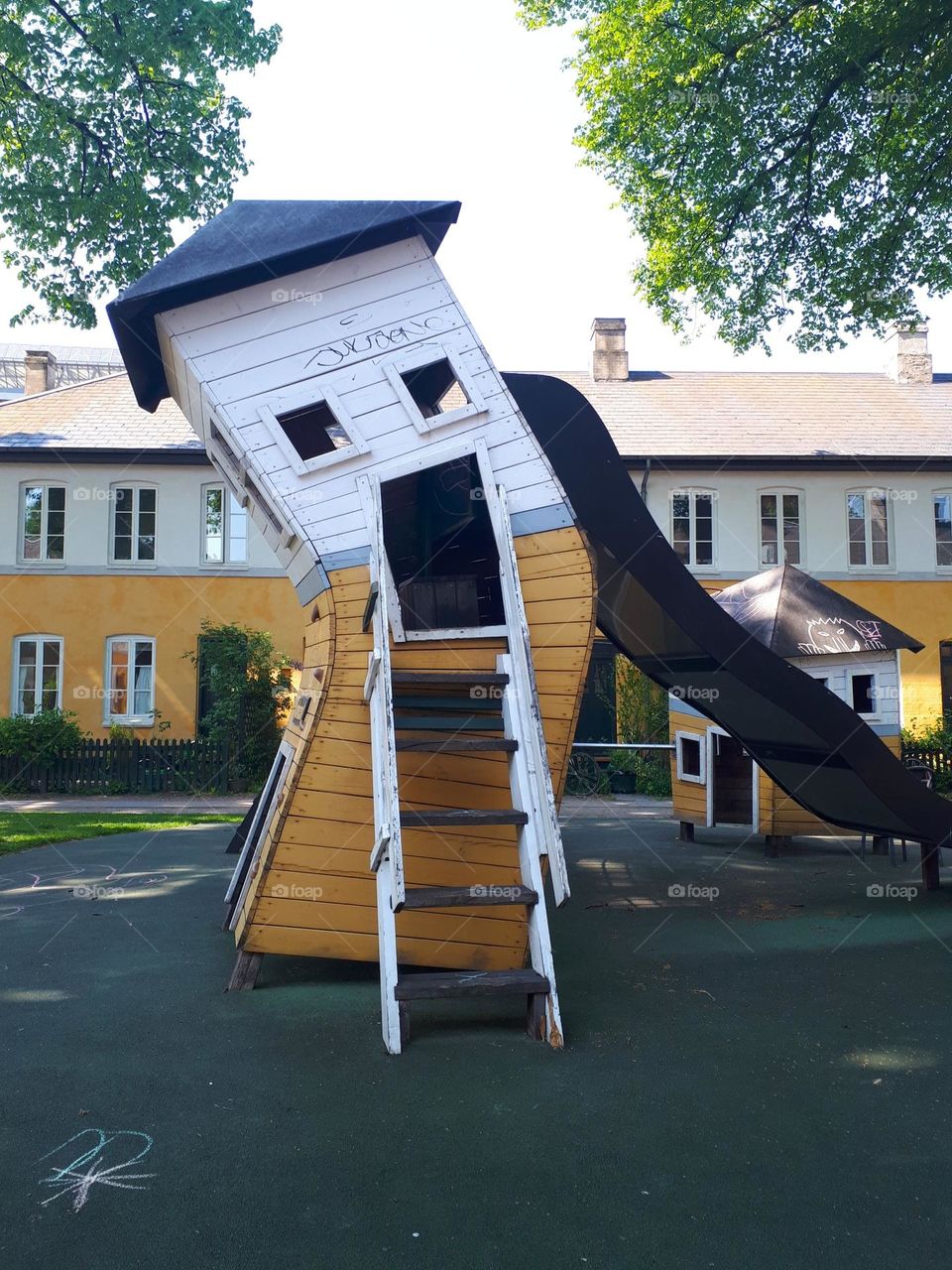 Children playgroung with funny yellow slide structure looking like a face with open mouth.