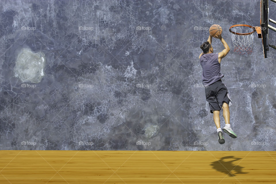 Basketball in hand man jumping Throw a basketball hoop On the wooden floor Background plaster wall loft  with The pattern of cracks.