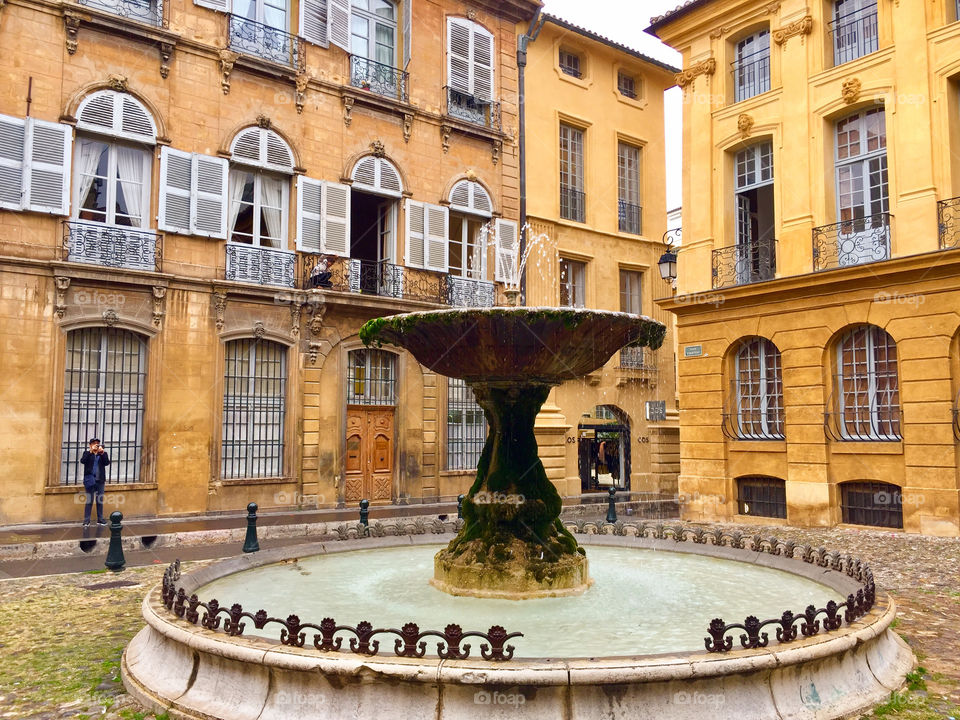 Old Fountain surrounded by rustic buildings in village square in Provence, France
