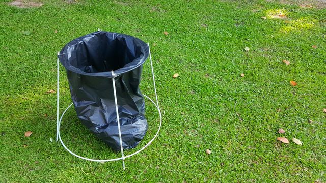 simple teporary recycle bin. teporary recycle bin made of black plastic bag and simple steel bar structure on green grass background