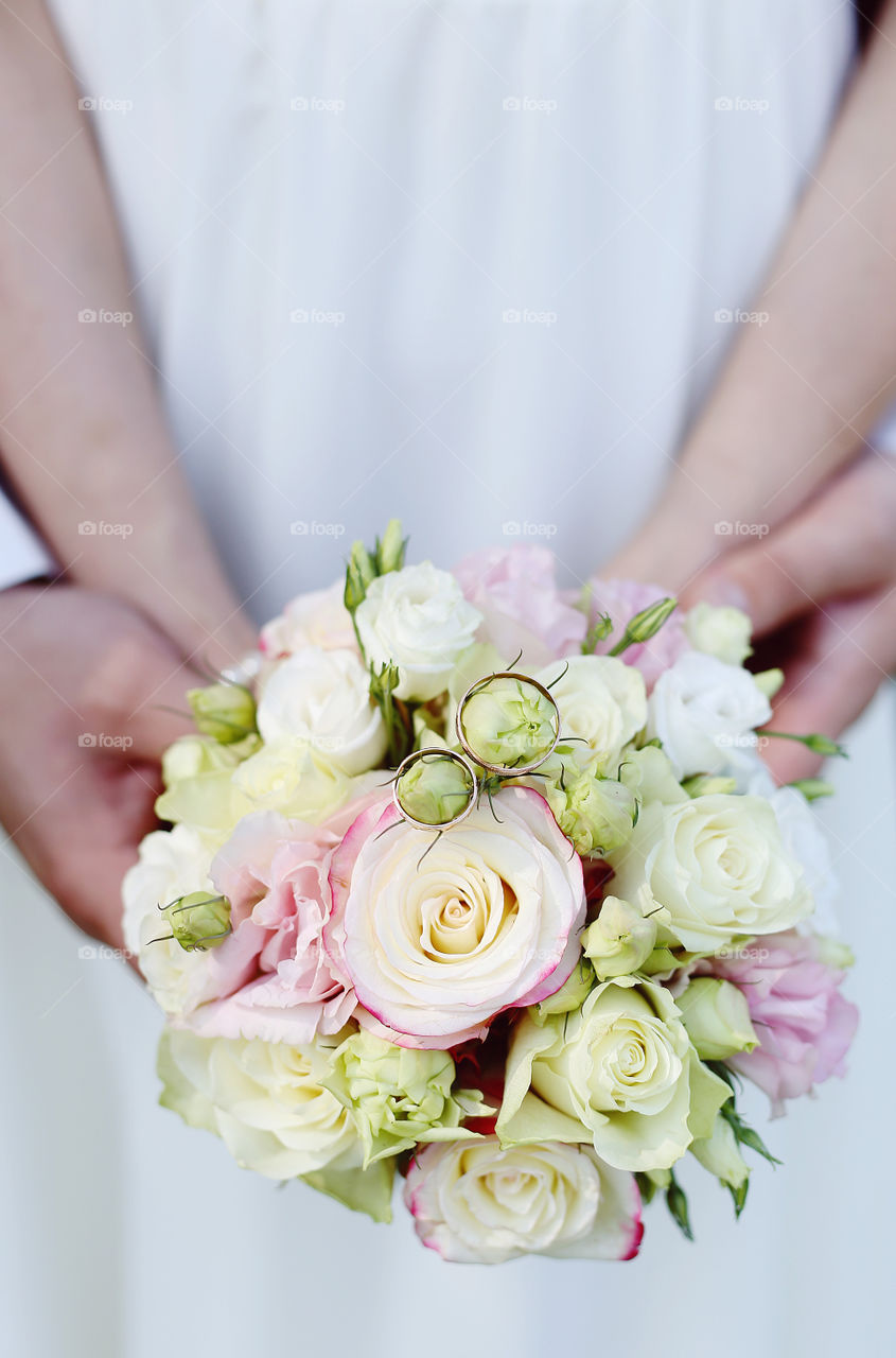 Hands holding bouquet of flower with two wedding ring