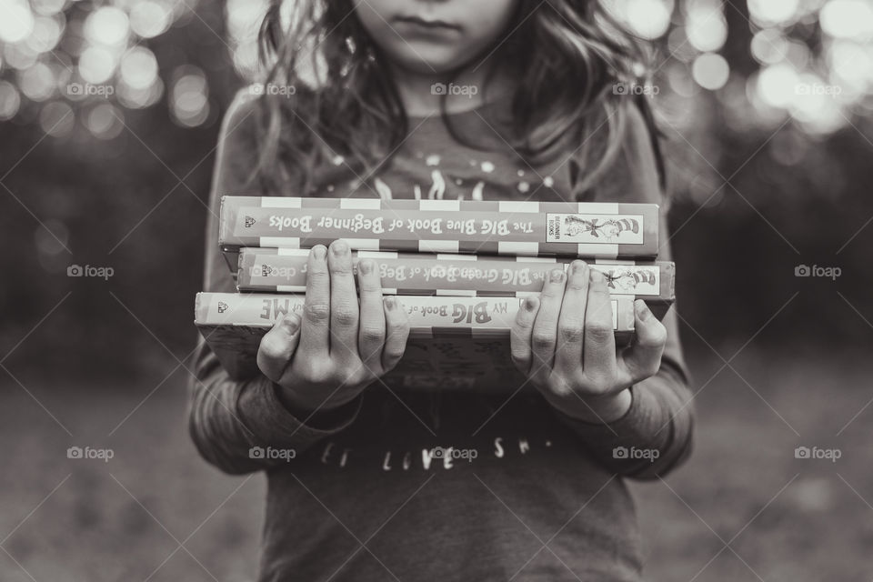 A girl holding a stack of books