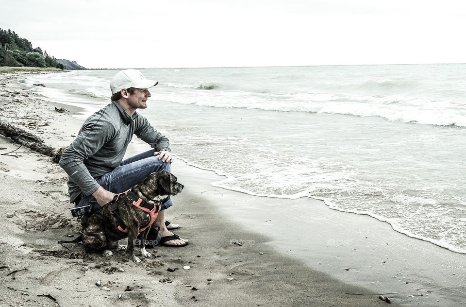 Man sitting with dog near beach