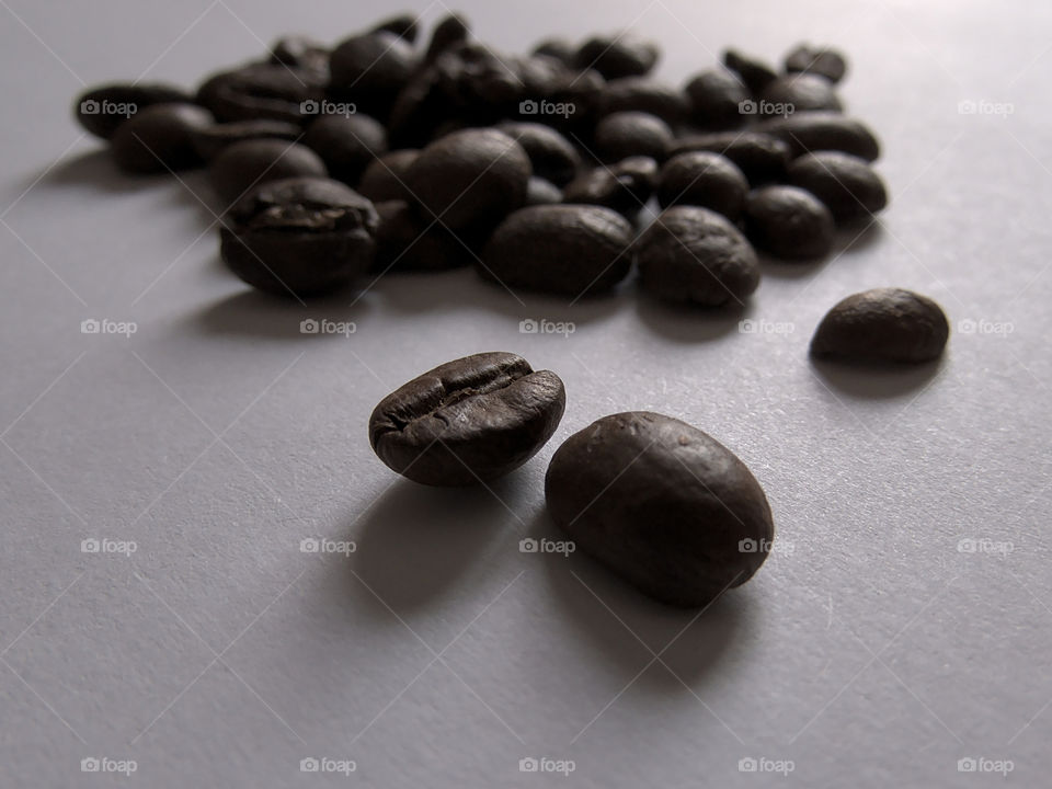 Close-up of roasted coffee beans on white surface and selective focus