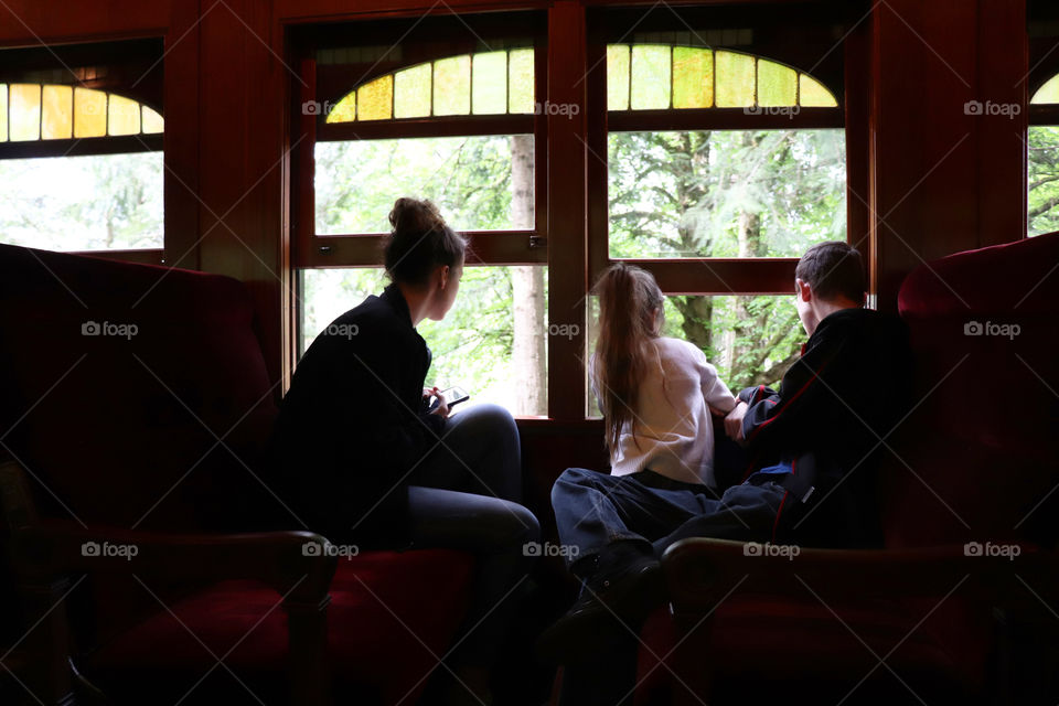 Siblings sitting by a window, looking out