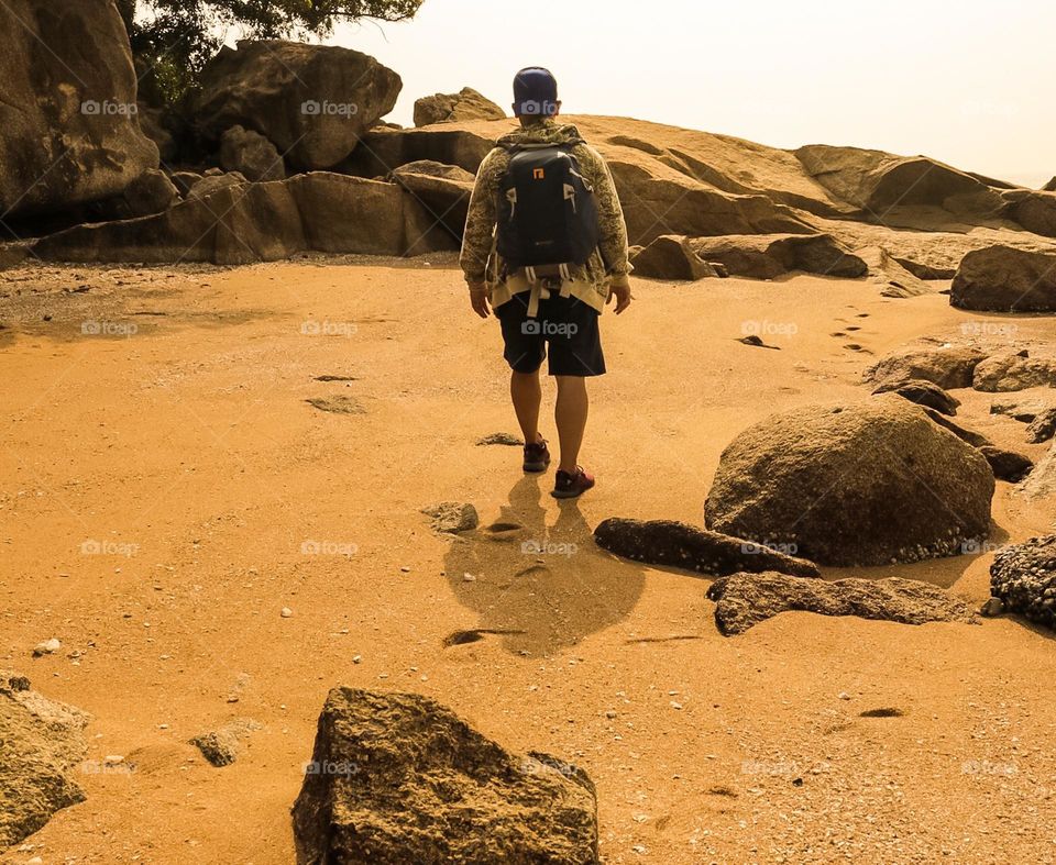 Rear view of a man walking on remote trail along the beach