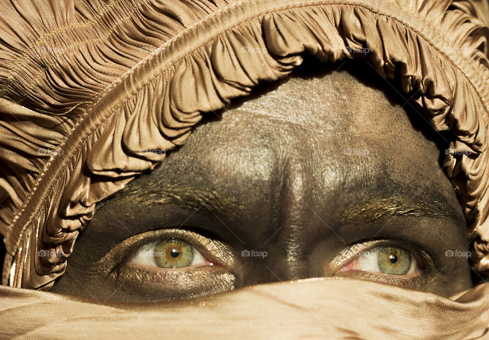 Woman's green eyes and head scarf in golden color