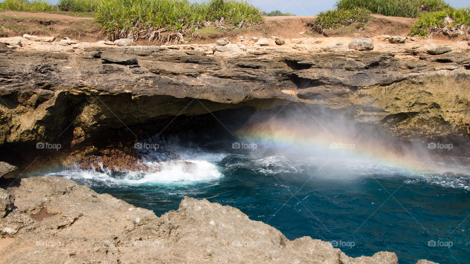 small rainbow at low tide at devil's tear of Nusa Lembongan Indonesia