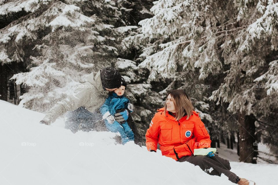 family of three having fun in the mountains in the fresh powdered snow