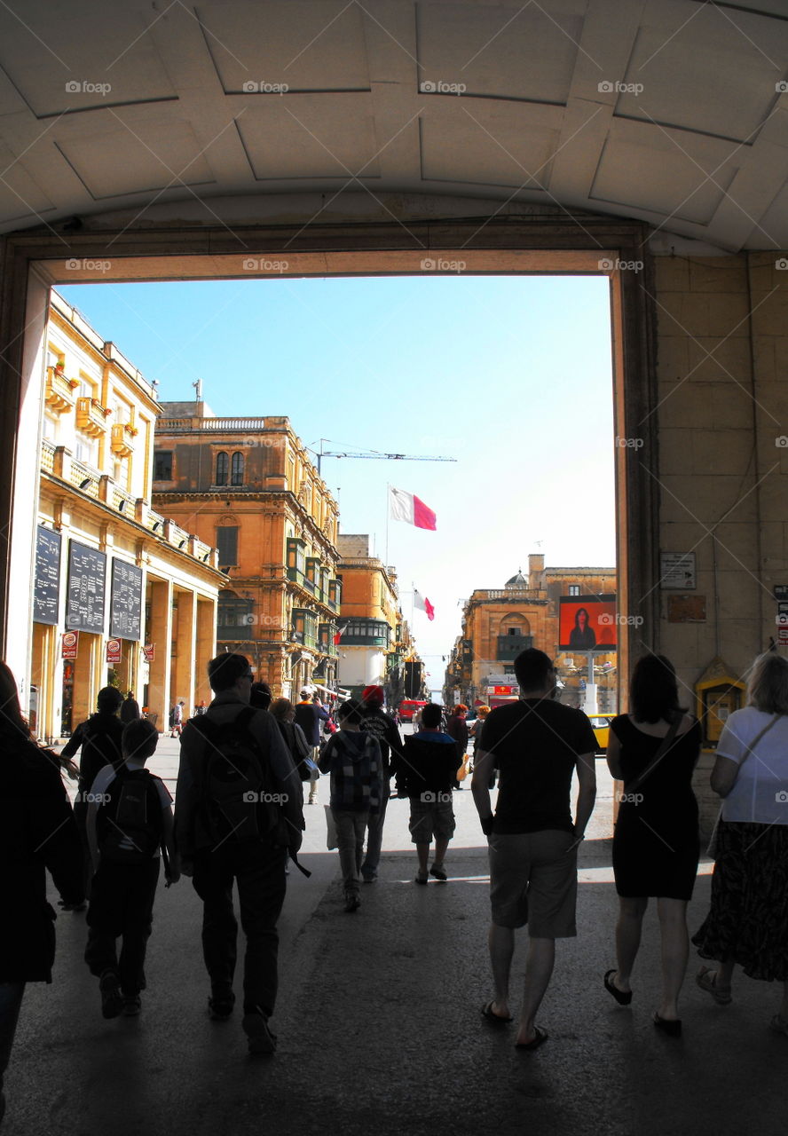 People emerging from under an arch in Valletta, Malta