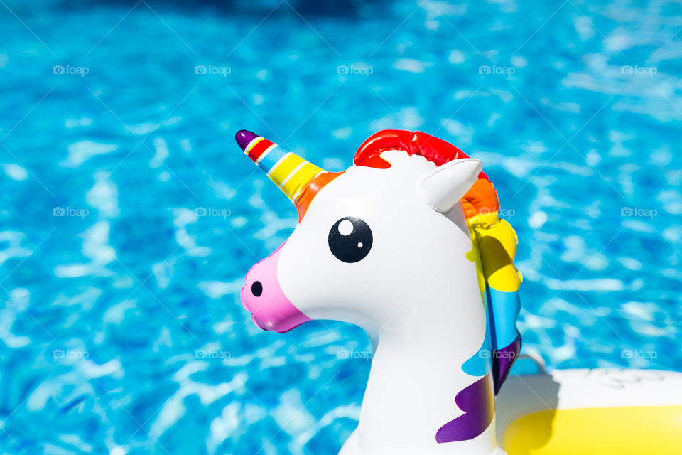 Inflatable colorful unicorn in swimming pool in the hotel. Summer vacation and travel concept