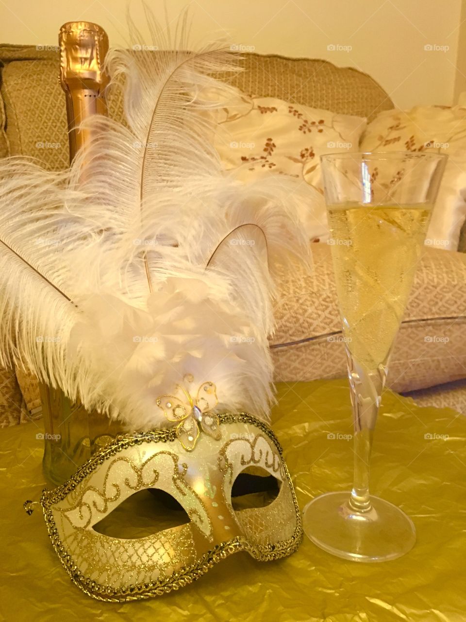 Gold Venetian masquerade mask with bottle of wine and a glass of white grape juice 