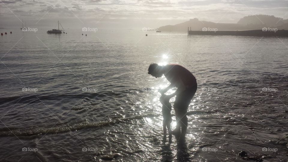 holding child's hand on beach at dawn