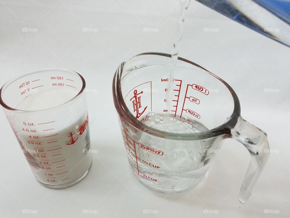 measuring cups with table sugar and water pouring