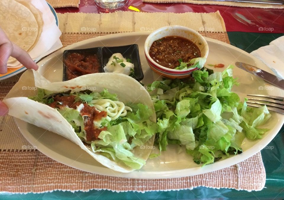 Soft shell beef tacos on the plate with a lot of infredients.