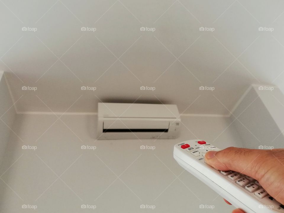 Hand on the air conditioner remote control