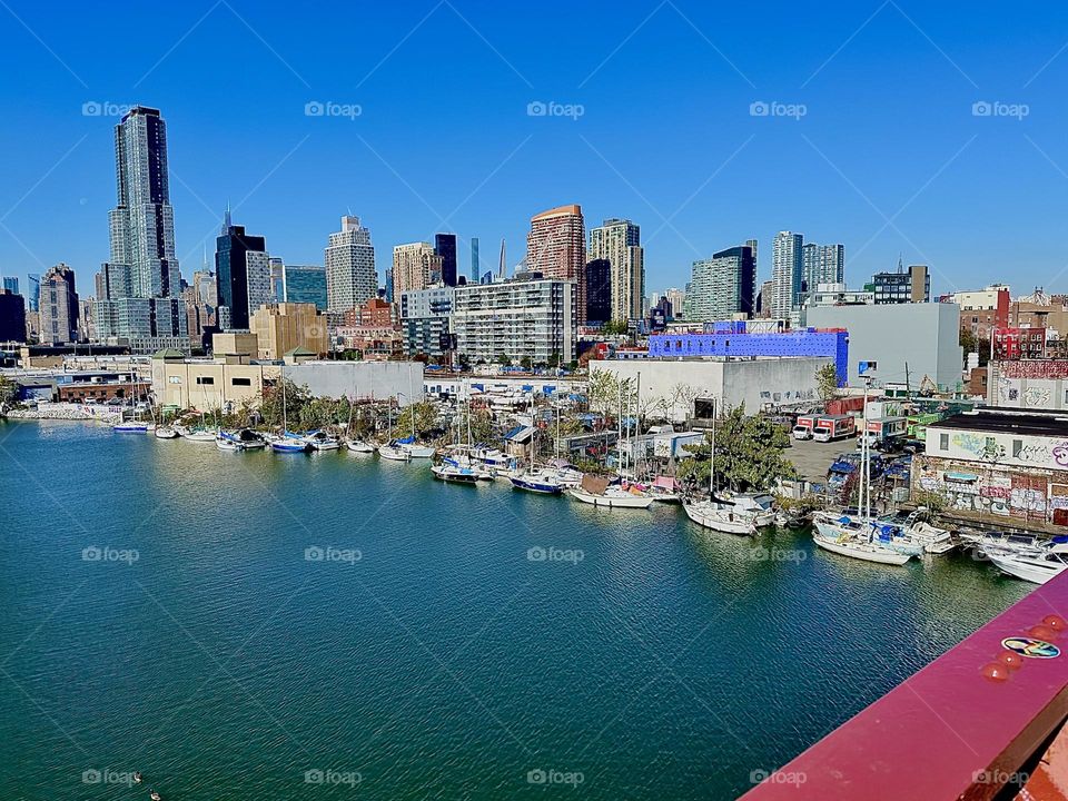 Seen from the „Pulaski Bridge“ this is „Newtown Creek“, an inlet of the „E River“. We are in the middle of the bridge halfway to „Greenpoint“, Bklyn that it connects to LIC visible straight ahead as well as „Manhattan“. 2023. Hypnotic Productions