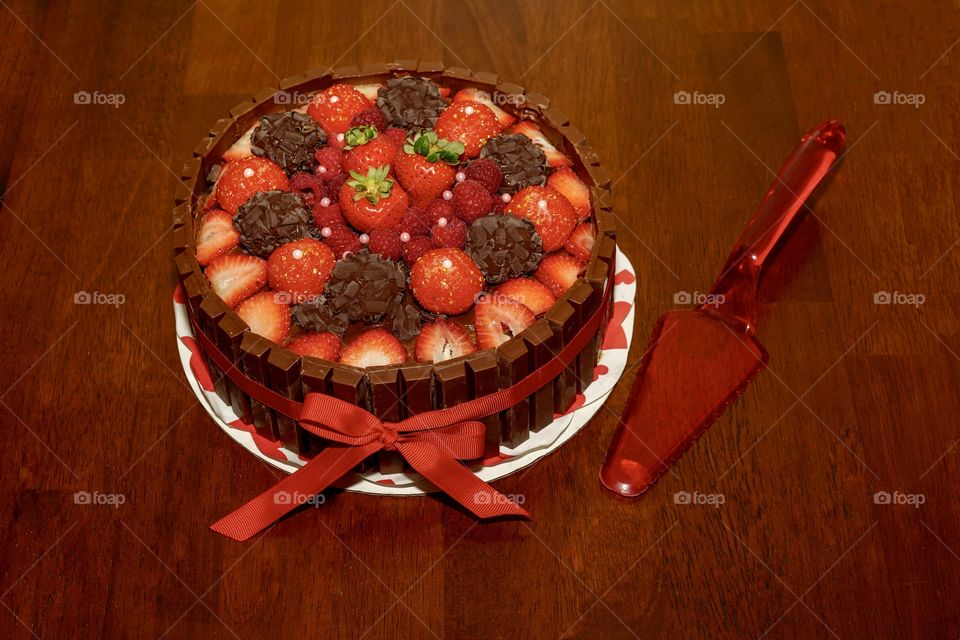 Delicious cake with chocolates, chocolate bars, and fruit