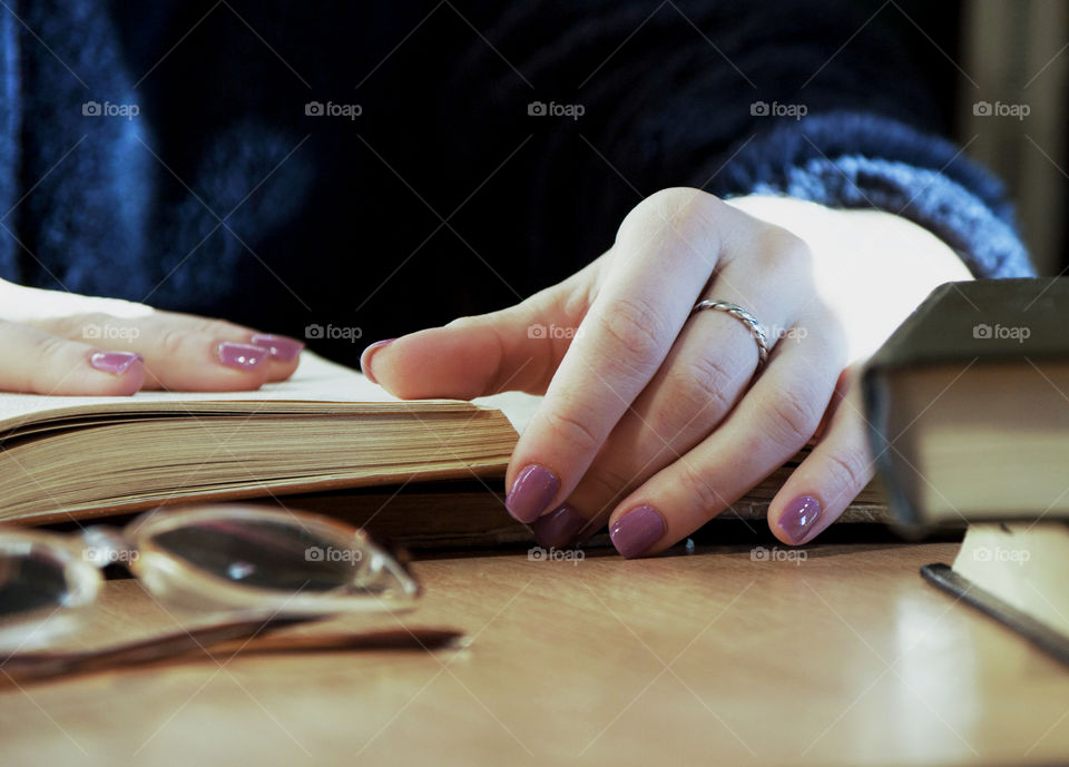 Close-up of girl's hand on book