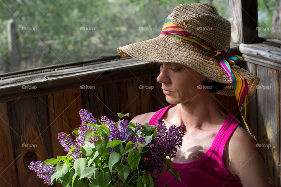 A woman on the balcony holds lilac flowers, springtime
