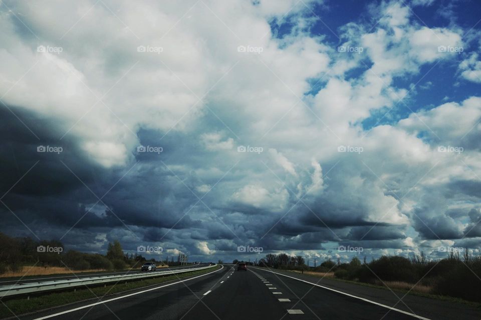 Big clouds above the road, blue black and white, heavy clouds above highway, dark and danger mood