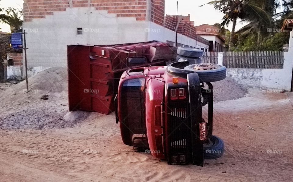red truck overturned by the weight of the sand