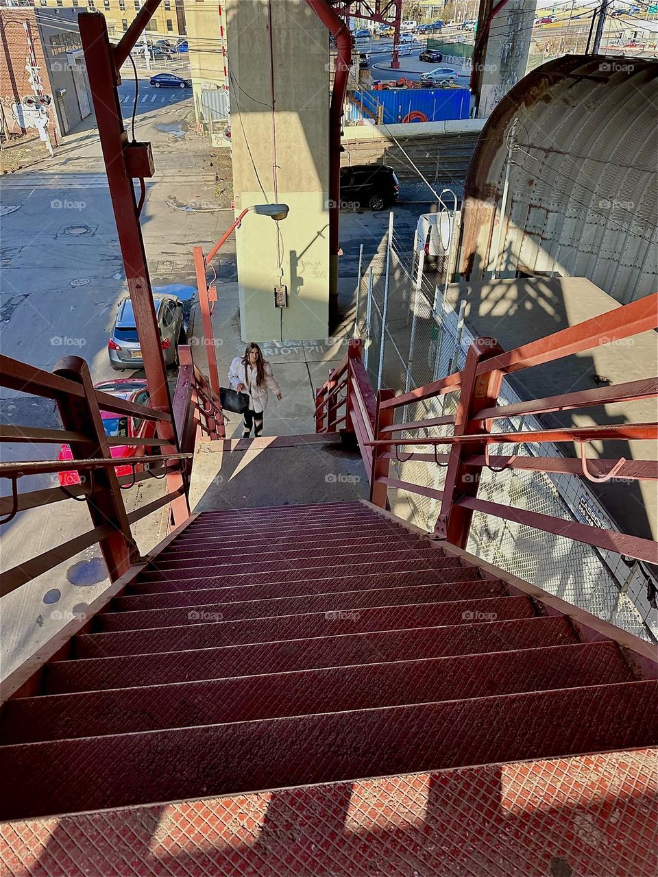 This is the red metal staircase of the “Pulaski Bridge” at “Newtown Creek” in LIC, Queens descending to street level in LIC. The structures as well as the shadows they cast combine to interesting ever changing patterns. 2023. Hypnotic Productions
