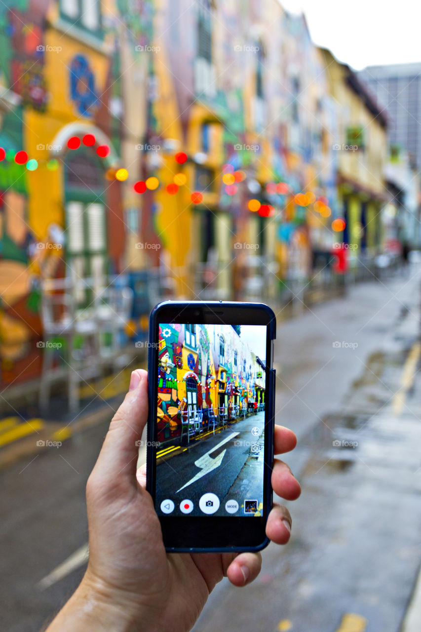 traveler exploring the city taking picture with mobile phone on the street in Singapore