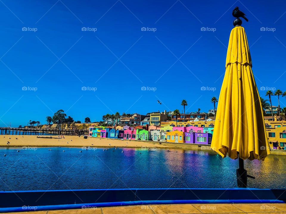 View from a patio in the Venetian in Capitola California with the yellow umbrella in foreground on the soquel river. With the wharf and beach