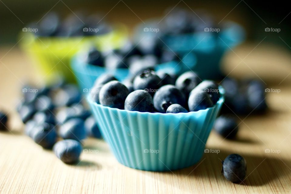 Fruits! - Blueberries in blue- and lime green-colored silicone baking cups on bamboo surface